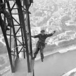 29 Jul 1924, Paris, France --- Original caption: 7/29/1924-Paris, France, : Workmen are shown atop the lofty Eiffel Tower, putting the last strokes to the job of repainting the great steel structure. Below, the city of Paris stretches forth. In this photo, a worker has one arm and leg on the structure, and one of each off, making for a daring pose. --- Image by © Bettmann/CORBIS